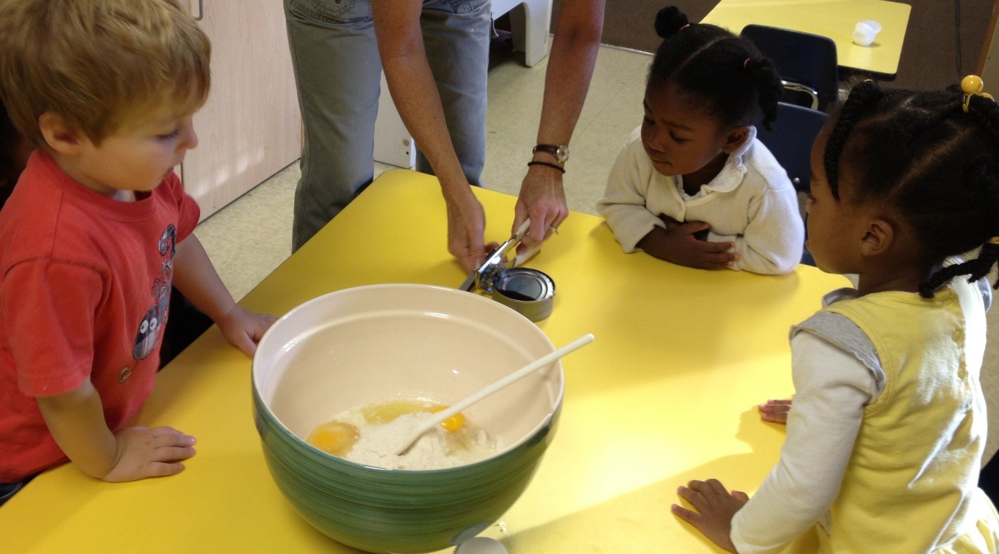 Children in aprons measuring and mixing ingredients