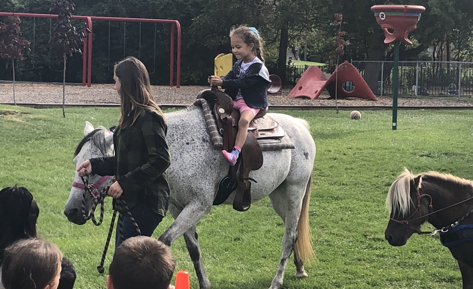 A child taking a pony ride during a summer program visit